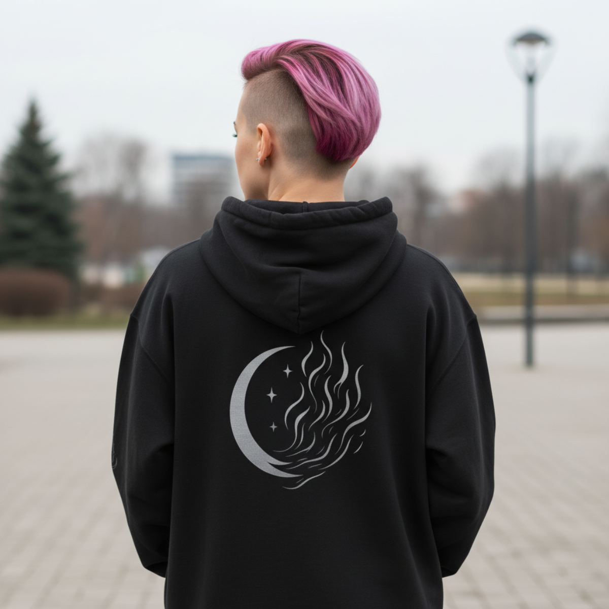 Person wearing a black hoodie with a design on the back, standing outdoors.