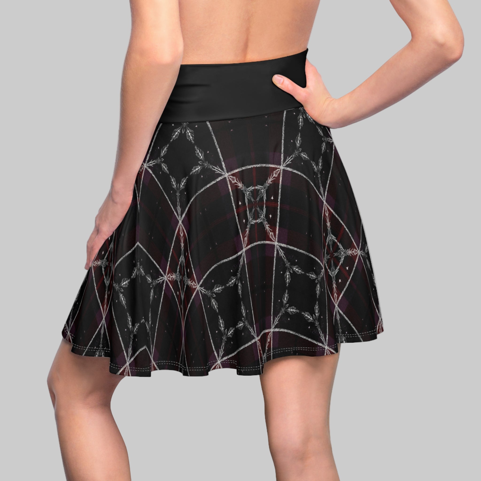 Black skirt with spider web pattern worn by a person on a white background