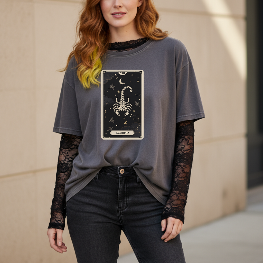 Person wearing a gray t-shirt with a Scorpio zodiac design, standing against a beige wall.