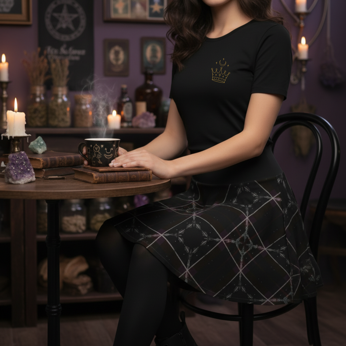Woman wearing a Shadow Weave Gothic Plaid Skater Skirt with celestial feather-sigil pattern, styled with the Spin in the Dark pocket sigil t-shirt, black tights, and combat boots sitting in a coffee shop.