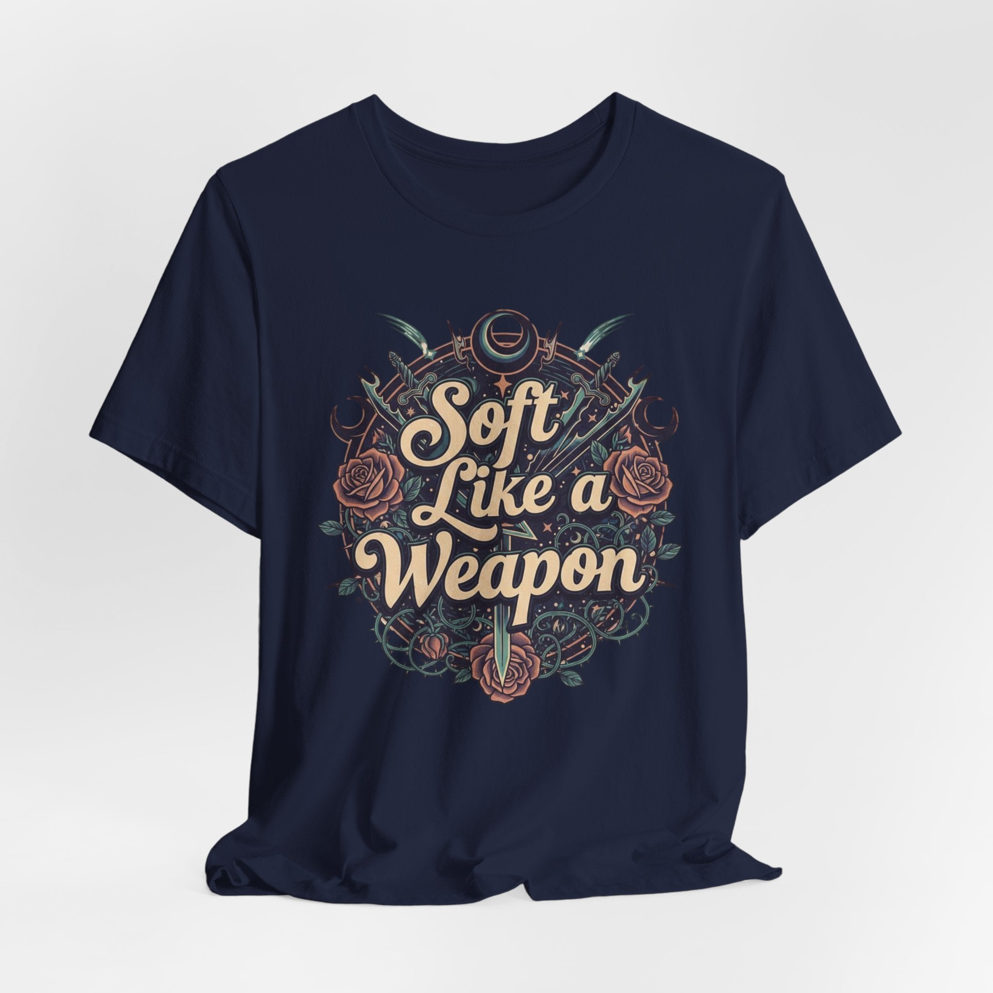 Navy blue t-shirt with 'Soft Like a Weapon' text and design on a light gray background