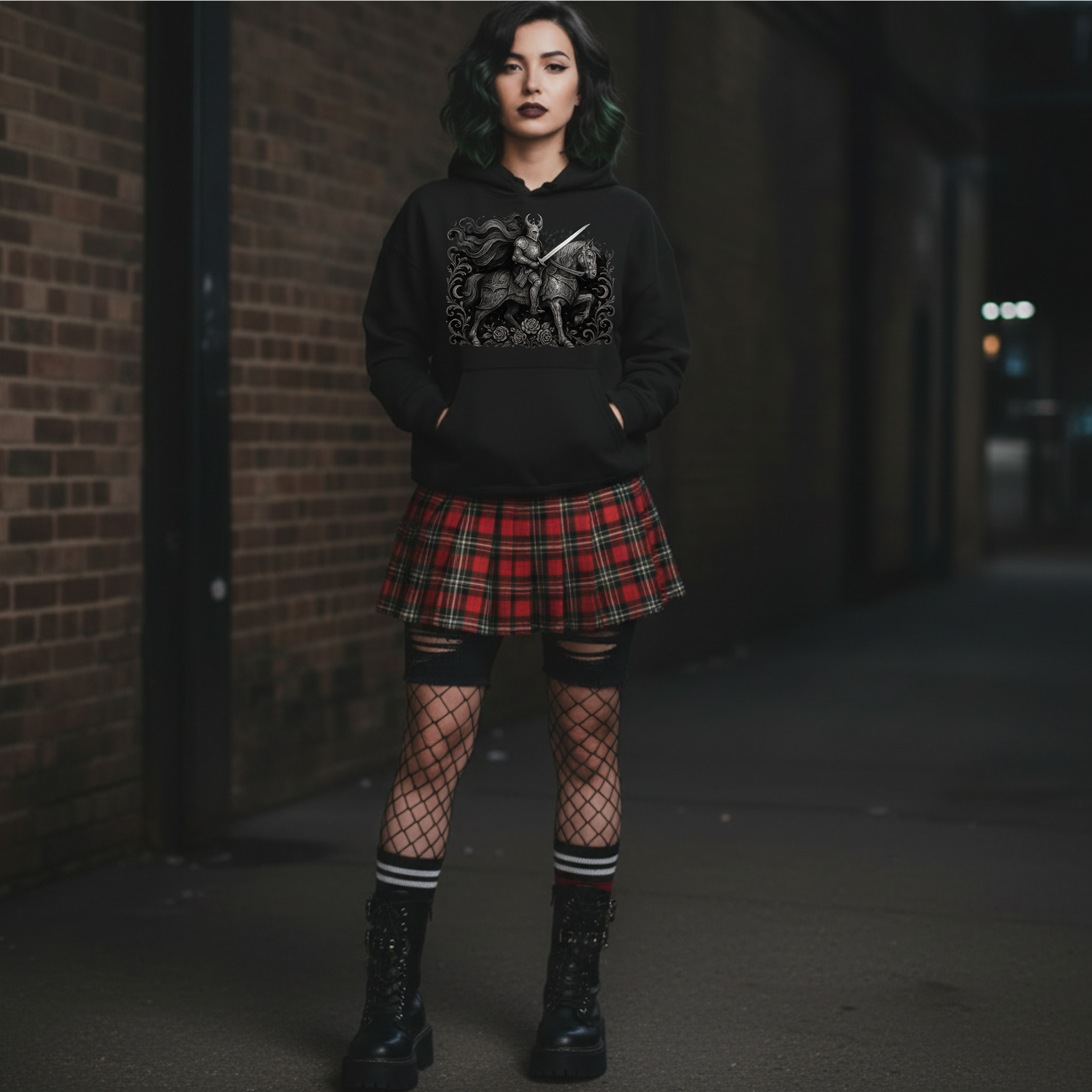 Person wearing a black hoodie with a graphic design, plaid skirt, fishnet stockings, and black boots in an alleyway.